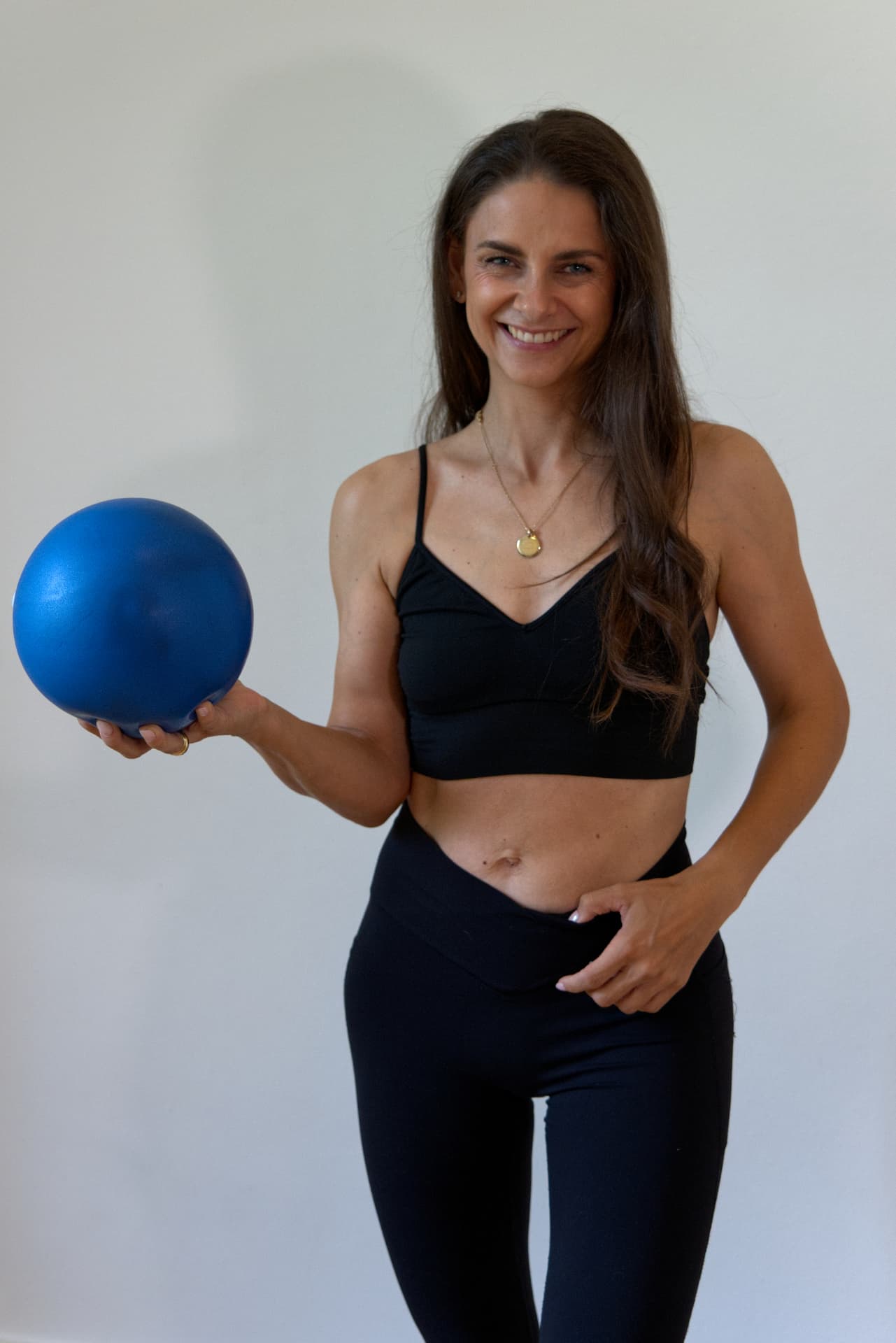Stephanie Newell holding a Pilates ball during an individual postpartum rehabilitation session
